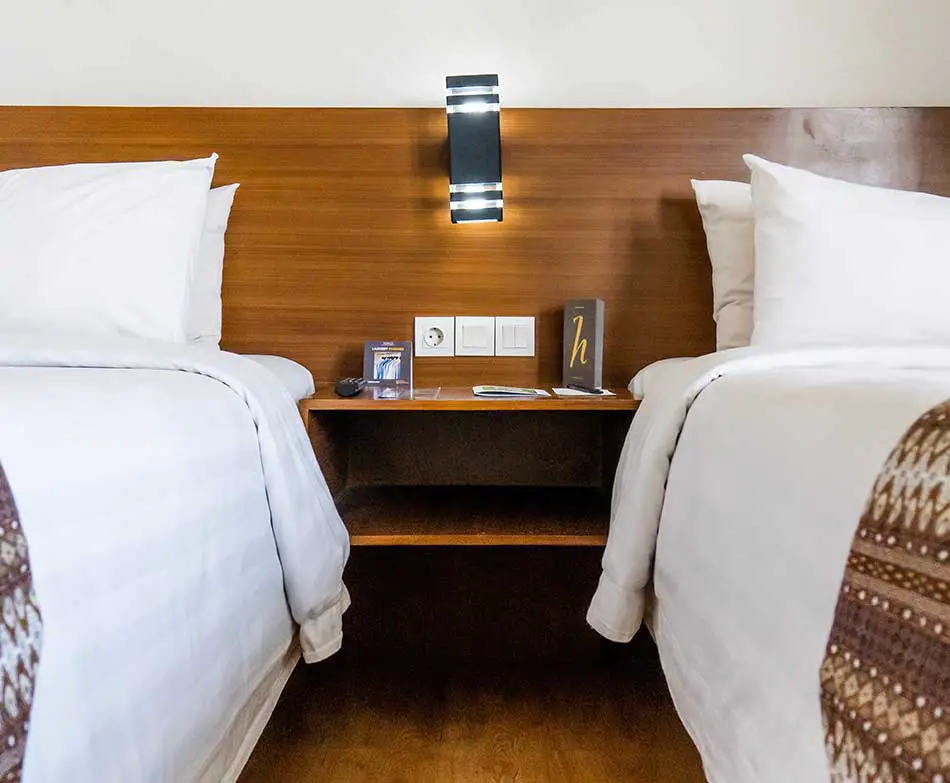 A nightstand between two beds in a hotel room.